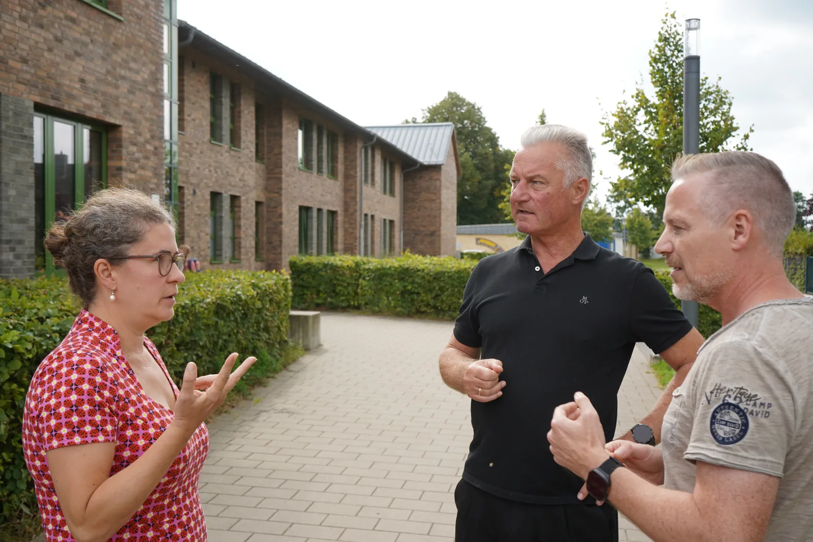 Frank Matthiesen im Gespräch mit zwei Menschen auf einem Weg zwischen Wohngebäuden.